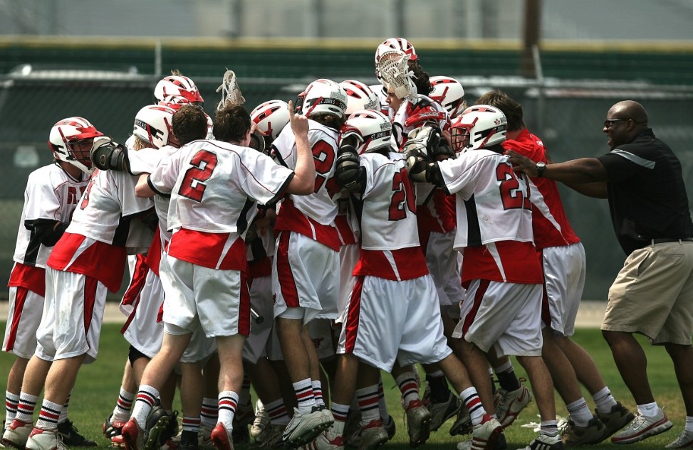 Boys lacrosse team celebrating with coach